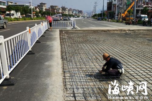 部分路面被挖开，工人正在铺设捆绑钢筋